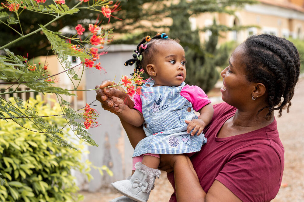 A TotoCare Connect Child & Home Assistant sharing a moment outdoors with a young child